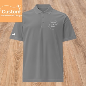 May include: Gray polo shirt with a white embroidered circle on the chest that says "Custom LOGO HERE".