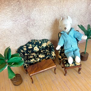 May include: A miniature living room set with a floral patterned couch, a small wooden table, and a plush toy mouse wearing blue pajamas sitting on a floral patterned armchair.