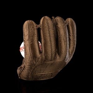 May include: A brown baseball glove with a baseball inside. The glove is made of textured leather and has visible stitching. The baseball is white with red stitching.