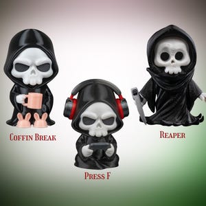 Puede incluir: Tres figuras de la Muerte con túnicas negras y caras de calavera. Una sostiene una taza y usa pantuflas de conejito, otra tiene auriculares y un controlador de juegos, y la tercera sostiene una guadaña. El texto en la imagen dice "COFFIN BREAK", "PRESS F" y "REAPER".