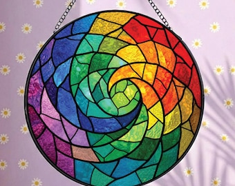 Op de afbeelding: Een ronde glas-in-lood zanger met een levendig regenboogkleurig spiraalpatroon. Het ontwerp bestaat uit talloze kleine, veelkleurige glazen segmenten die bijeengehouden worden door donkere metalen lijnen, opgehangen aan een dunne zwarte metalen ketting.