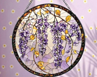 Op de afbeelding: Een ronde glas-in-lood zonnevanger met een gedetailleerd ontwerp van neerhangende paarse blauweregenbloemen en gele bladeren tegen een lichte achtergrond, gevat in een donker metalen frame en opgehangen aan een dunne zwarte metalen ketting.