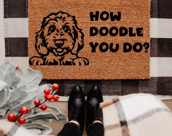 May include: A rectangular doormat made of natural coir fiber. It features a black illustration of a dog's face and the phrase "HOW DOODLE YOU DO?" in black block letters. The mat is placed on a black and white checkered rug.