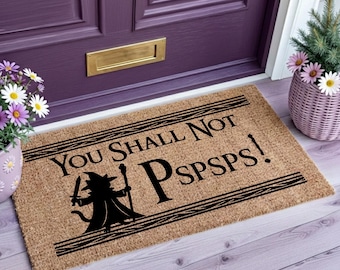 Op de afbeelding: Een rechthoekige beige kokosmat met zwarte tekst "YOU SHALL NOT PSPSPS!" en een zwart silhouet van een kat verkleed als tovenaar met een staf en zwaard, omlijst door twee horizontale zwarte lijnen boven en onder het ontwerp.
