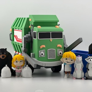 Peut inclure: Un jouet camion poubelle vert avec un panneau latéral blanc et rouge, accompagné de figurines représentant un ours noir, un enfant blond, un rat et un raton laveur. L'ensemble comprend une benne bleue, plusieurs petits sacs blancs et deux sacs noirs.