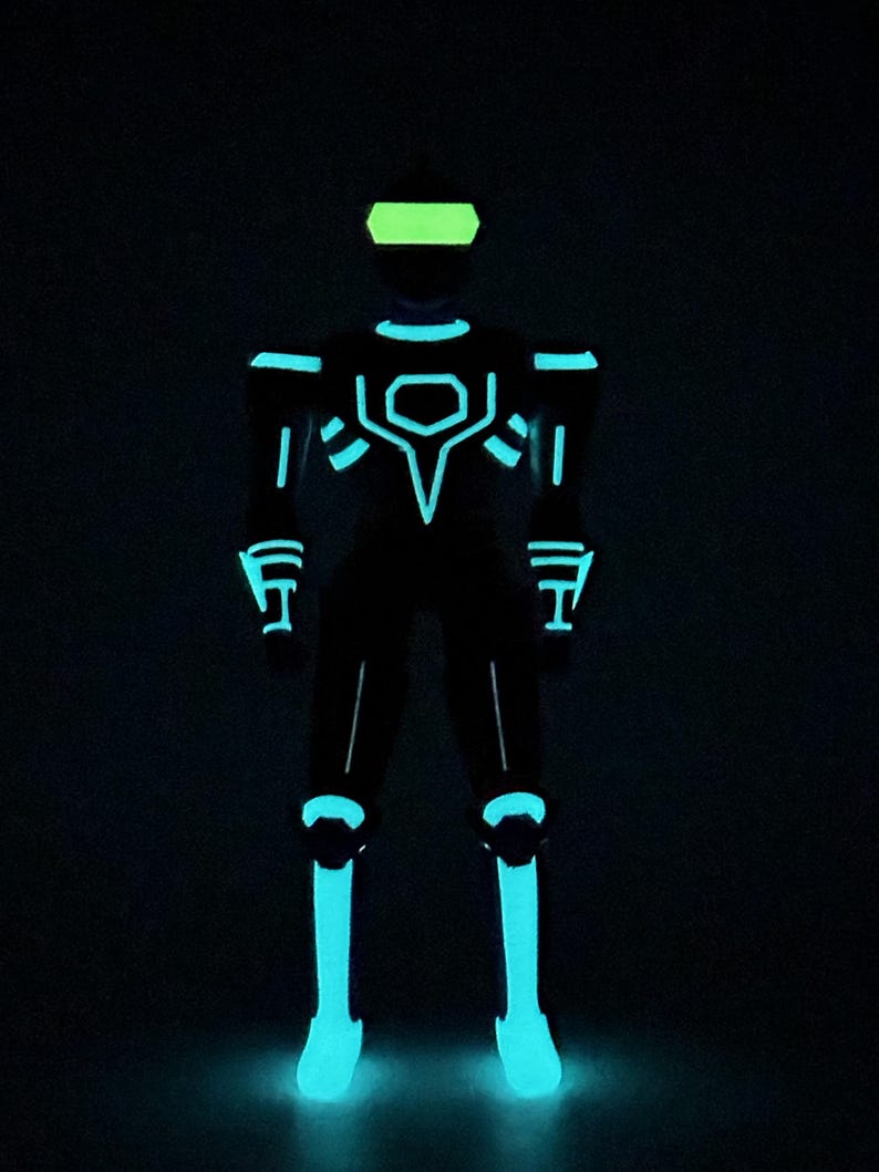 May include: A full-body suit featuring glowing cyan light strips arranged in geometric patterns across the chest, shoulders, arms, and legs, paired with a bright lime green visor, all set against a completely black background.