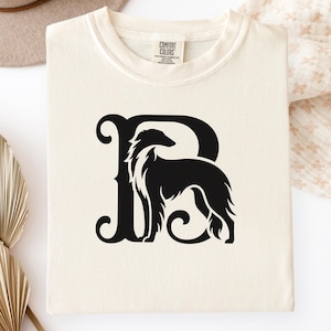 Pu&ograve; includere: Felpa color crema con grafica nera di un cane all'interno di una lettera "B" stilizzata. La felpa ha un girocollo e il marchio "Comfort Colors" &egrave; visibile sull'etichetta.