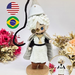 Pode incluir: Boneco de crochê com cabelo branco, chapéu pontudo branco, túnica branca, cinto preto, capa cinza com detalhes dourados e botas marrons. O boneco usa um monóculo e está sobre uma base circular. Texto: PDF PATTERN / PADRÃO DIGITAL e QIFREY.