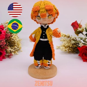 Może przedstawiać: Szydełkowa lalka Zenitsu z żółto-pomarańczowymi włosami i pasującym płaszczem. Lalka ma na sobie czarny strój z białym paskiem i żółto-pomarańczowymi butami. Widoczny jest tekst "ZENITSU" i "PDF PATTERN / PADRÃO DIGITAL".