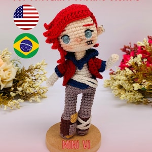 May include: A crocheted doll of the character Mini Vi from Arcane, with red hair, a red jacket, and gray pants. The doll is standing on a wooden base. The text "PDF PATTERN / PADRÃO DIGITAL" is at the top, and "Mini Vi (Arcane)" is at the bottom.