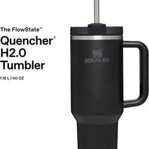 K&ouml;nnte beinhalten: Schwarzer Stanley Quencher H2.0 Tumbler mit Griff und Strohhalm. Der Becher hat das Stanley-Logo und fasst 1,18 L. Der Text auf der Seite lautet "The FlowState Quencher H2.0 Tumbler".