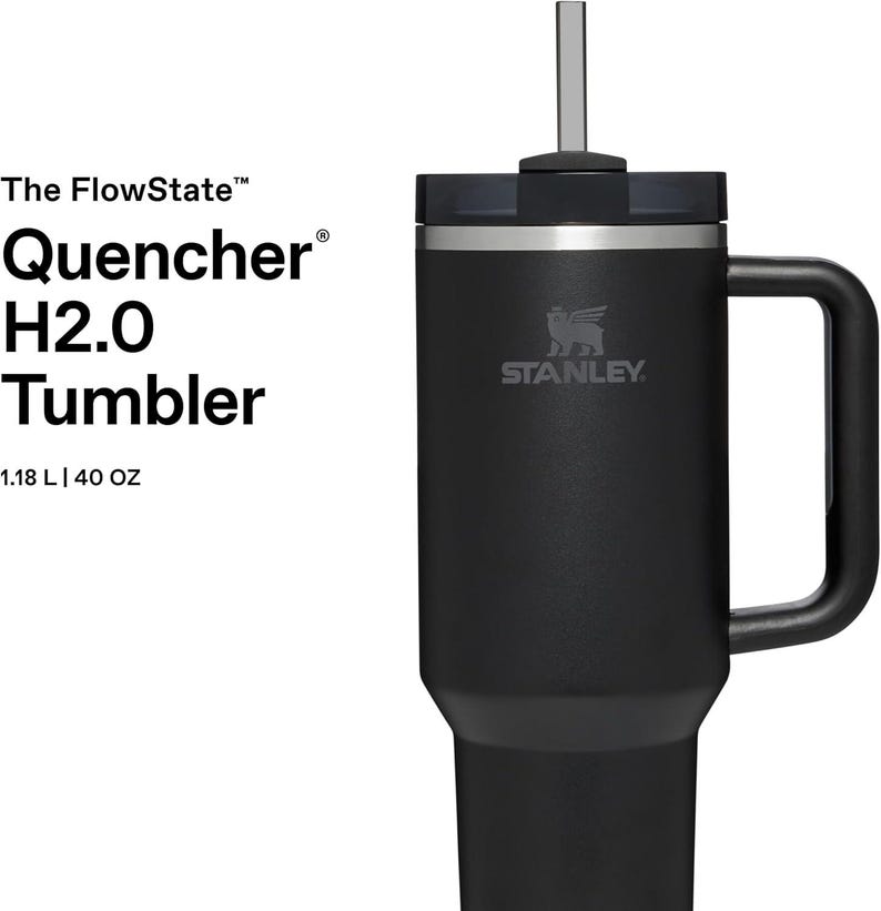 K&ouml;nnte beinhalten: Schwarzer Stanley Quencher H2.0 Tumbler mit Griff und Strohhalm. Der Becher hat das Stanley-Logo und fasst 1,18 L. Der Text auf der Seite lautet "The FlowState Quencher H2.0 Tumbler".