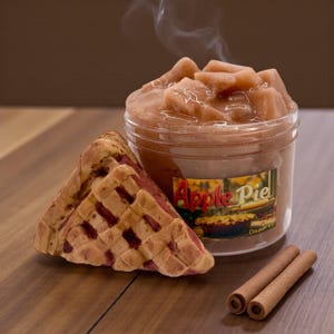 May include: A clear plastic container filled with apple pie filling, a slice of pie, and two cinnamon sticks. The container has a label that reads "Apple Pie". The pie slice has a lattice crust.