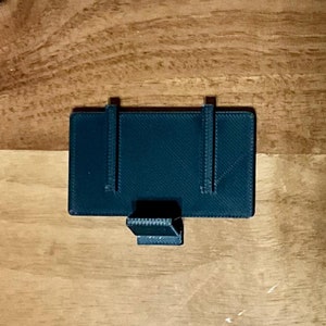 May include: A black 3D printed phone stand with a simple design. The stand has two vertical supports and a horizontal base.