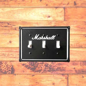 May include: A black wall plate with the word "Marshall" in white lettering and three white toggle switches.