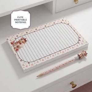Pode incluir: Um bloco de notas retangular com fundo rosa claro decorado com pequenos corações e uma área central com linhas horizontais. O bloco apresenta uma ilustração de vaca e o texto CUTE PRINTABLE NOTEPAD. Inclui um lápis a condizer com um topo de vaca.