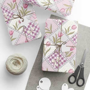 May include: Gift-wrapped presents with floral and gingham patterns, tied with twine and blank tags. The wrapping paper features pink tulips and bows. A ball of twine, scissors, and tags are also visible.