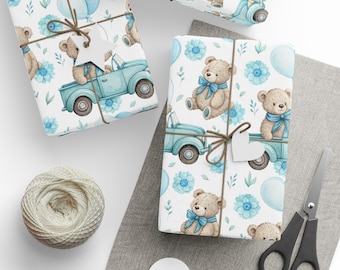 May include: Gift wrap featuring a repeating pattern of teddy bears, blue trucks, balloons, and floral accents on a white background. The gifts are tied with twine and adorned with heart-shaped tags. A ball of twine and scissors are also present.