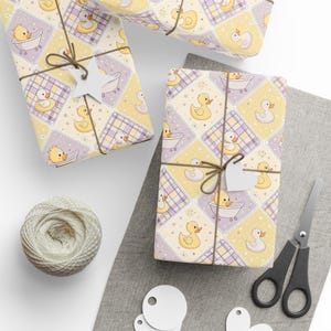 May include: Wrapped presents featuring a yellow and purple duck design, tied with twine and a star-shaped tag. A ball of twine, scissors, and blank tags are also visible, suggesting a baby shower or children's gift theme.