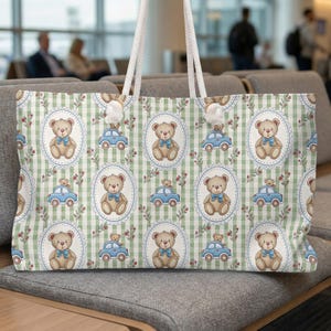 May include: A large tote bag with a repeating pattern of teddy bears, blue cars, and floral accents on a green and white checkered background. The bag has white rope handles and is sitting on a gray sofa.