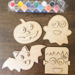 May include: A Halloween-themed craft kit featuring four wooden cutouts: a pumpkin, ghost, bat, and Frankenstein's monster. Includes a set of colorful paints and a paintbrush for decorating the wooden shapes. Perfect for a fun, creative activity.