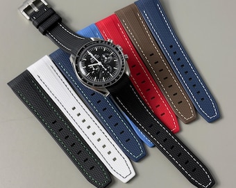 May include: A stainless steel chronograph watch with a black dial and tachymeter bezel, attached to a black textured rubber strap with white stitching, displayed alongside five additional rubber watch straps in white, blue, red, brown, and navy.
