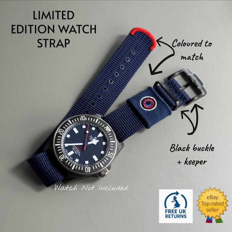 Puede incluir: Una correa de reloj tejida en azul marino con una punta cosida en rojo, una hebilla negra y una trabilla negra con un emblema circular rojo, blanco y azul. La correa se muestra con un reloj negro. El texto incluye: LIMITED EDITION WATCH STRAP.
