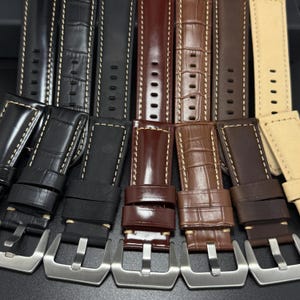 May include: A collection of leather watch straps in various colors, including black, brown, and tan. The straps feature contrasting stitching and stainless steel buckles. Some straps have a textured, crocodile-like pattern.
