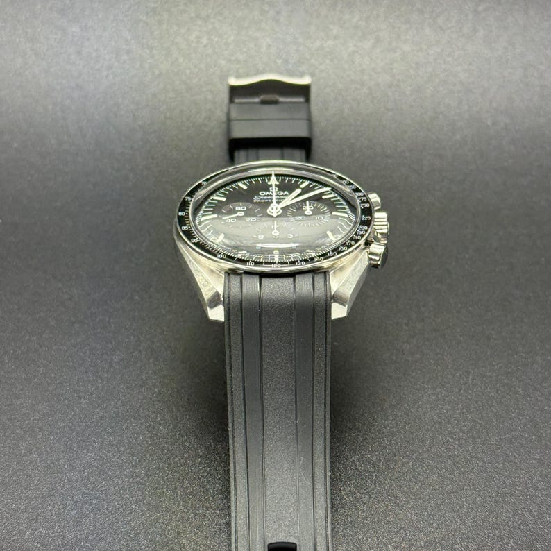 Puede incluir: Un reloj de pulsera plateado con esfera negra y correa de caucho negra. El reloj tiene una esfera redonda con agujas y marcadores blancos. El reloj es de dise&ntilde;o cl&aacute;sico.