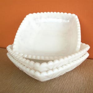 May include: Two white milk glass bowls with a beaded edge. The bowls are stacked on top of each other.