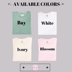 Puede incluir: Cuatro camisetas dobladas en diferentes colores: Bay, White, Ivory y Blossom. El texto "AVAILABLE COLORS" est&aacute; en la parte superior. La marca "Faith and Fine" est&aacute; en la parte inferior.