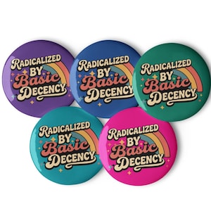 Może przedstawiać: Pięć okrągłych przypinek w odcieniach fioletu, niebieskiego, turkusowego, zielonego i różowego. Każda przypinka zawiera tekst "RADICALIZED BY Basic DECENCY" w stylu retro, z tęczą i wzorem gwiazd.