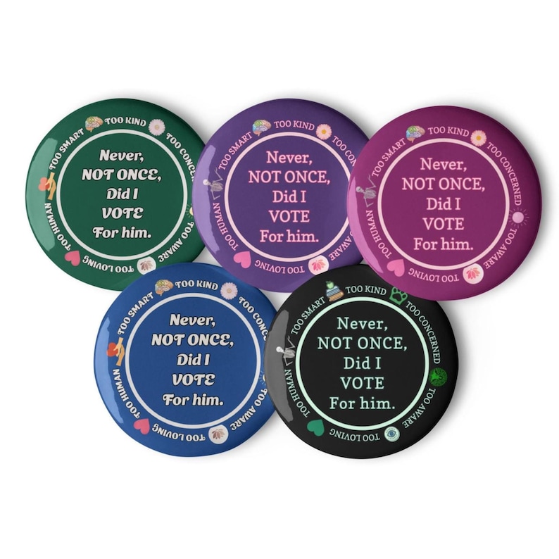 Op de afbeelding: Een verzameling van vijf ronde buttons in verschillende kleuren: groen, paars, blauw en zwart. Elke button bevat de tekst "Never, NOT ONCE, Did I VOTE For him." en andere zinnen zoals "Too Smart" en "Too Human."
