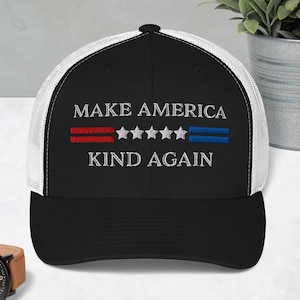 May include: A black and white trucker hat with a red, white, and blue embroidered design that says "Make America Kind Again".