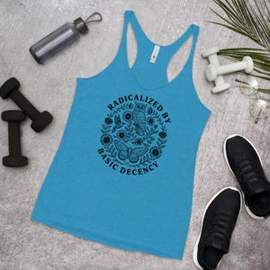 May include: A turquoise racerback tank top with the text "RADICALIZED BY BASIC DECENCY" in a circular design featuring an owl, butterfly, and flowers. Black dumbbells, a water bottle, and black sneakers are also visible.