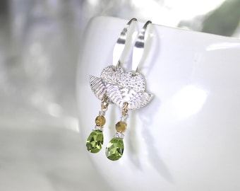 Puede incluir: Pendientes de plata con un diseño de hoja texturizada y gotas de piedras preciosas verdes.