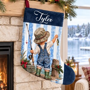 May include: A personalized Christmas stocking in navy blue and white with a graphic of a child in denim overalls and a bucket hat fishing on a dock. The name Tyler is printed in white script on the navy blue cuff. The background features snowflakes.