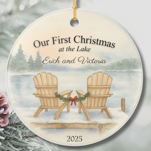 May include: Round ceramic Christmas ornament with a lake scene. The ornament features two wooden Adirondack chairs, a lake, and the text "Our First Christmas at the Lake Erich and Victoria 2025."