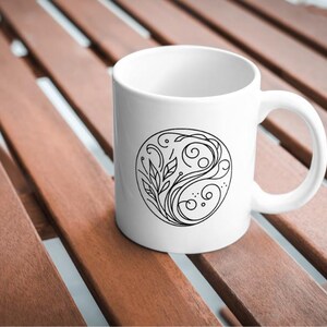 May include: White ceramic mug with a black and white design of a stylized floral and wave pattern inside a circle.