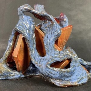 May include: A blue and brown ceramic sculpture with a flowing, abstract design. The sculpture features a series of stacked rectangular shapes.