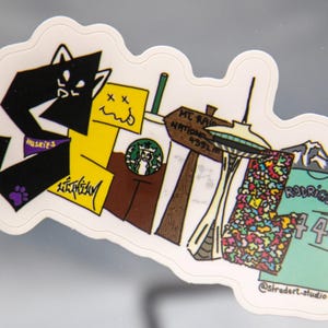 May include: A die-cut sticker featuring cartoon illustrations of a black cat, a yellow character, a Starbucks cup, the Space Needle, a jersey with the name Rodriguez and the number 44, and a mountain sign that reads Mt. Rainier National 4391m.