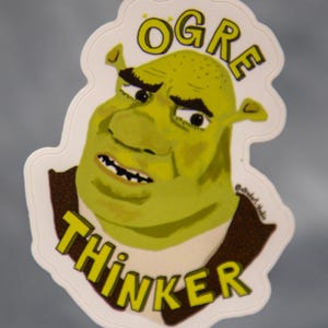 May include: A white sticker with a green ogre face and the text "OGRE THINKER" in yellow letters.