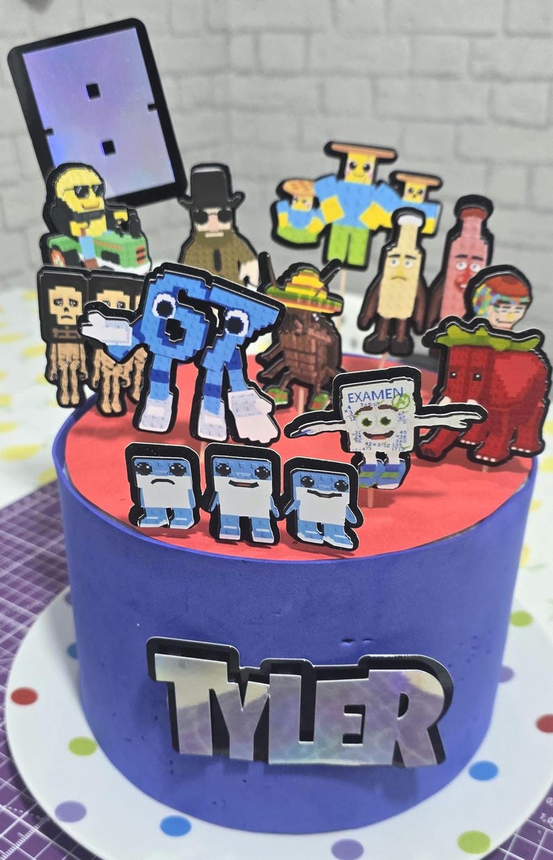 May include: A blue frosted cake with a red top, decorated with pixelated character toppers. The cake has the name "TYLER" on the side. The toppers include various figures, some holding signs, and a tablet-shaped decoration.