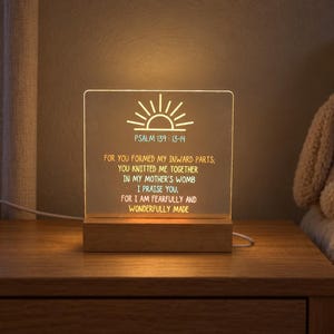 May include: A rectangular acrylic night light with a wooden base, featuring an engraved sun icon and the text: PSALM 139:13-14, FOR YOU FORMED MY INWARD PARTS, YOU KNITTED ME TOGETHER IN MY MOTHER'S WOMB I PRAISE YOU, FOR I AM FEARFULLY AND WONDERFULLY MADE.