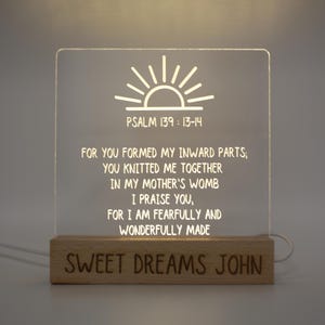 May include: A clear acrylic night light with the text "PSALM 139: 13-14" and a Bible verse. The light sits on a wooden base with the engraved words "SWEET DREAMS JOHN". The light is illuminated, creating a soft glow.