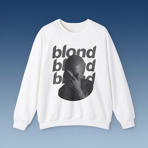 May include: White sweatshirt with a black and white image of a person covering their face with their hand. The text "blond" is repeated three times on the sweatshirt.