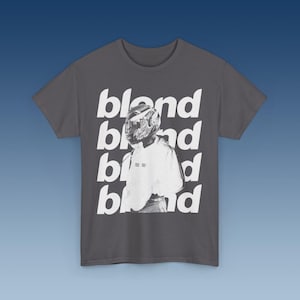 May include: A charcoal grey t-shirt with a white graphic print of a person wearing a helmet and the word "blond" repeated four times.