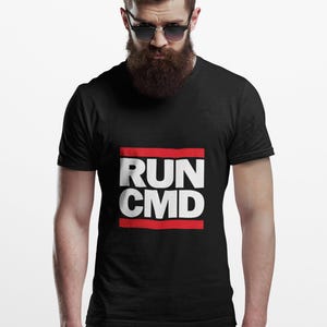 Könnte beinhalten: Schwarzes T-Shirt mit dem weißen Text "RUN CMD", eingerahmt von zwei roten Linien. Das T-Shirt wird von einer Person mit Bart und Sonnenbrille getragen.