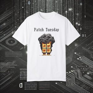 Puede incluir: Camiseta blanca con el texto "Patch Tuesday" sobre un gráfico de un edificio en llamas con cuatro ventanas y llamas. El edificio está rodeado de humo negro. El diseño está centrado en la camiseta.