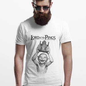 May include: White t-shirt with a black graphic of a creature holding a WiFi Pineapple. The text "LORD of the PINGS" is above the graphic. The shirt is worn by a person wearing sunglasses.